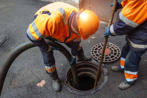 Tech sticking hose into sewer manhole